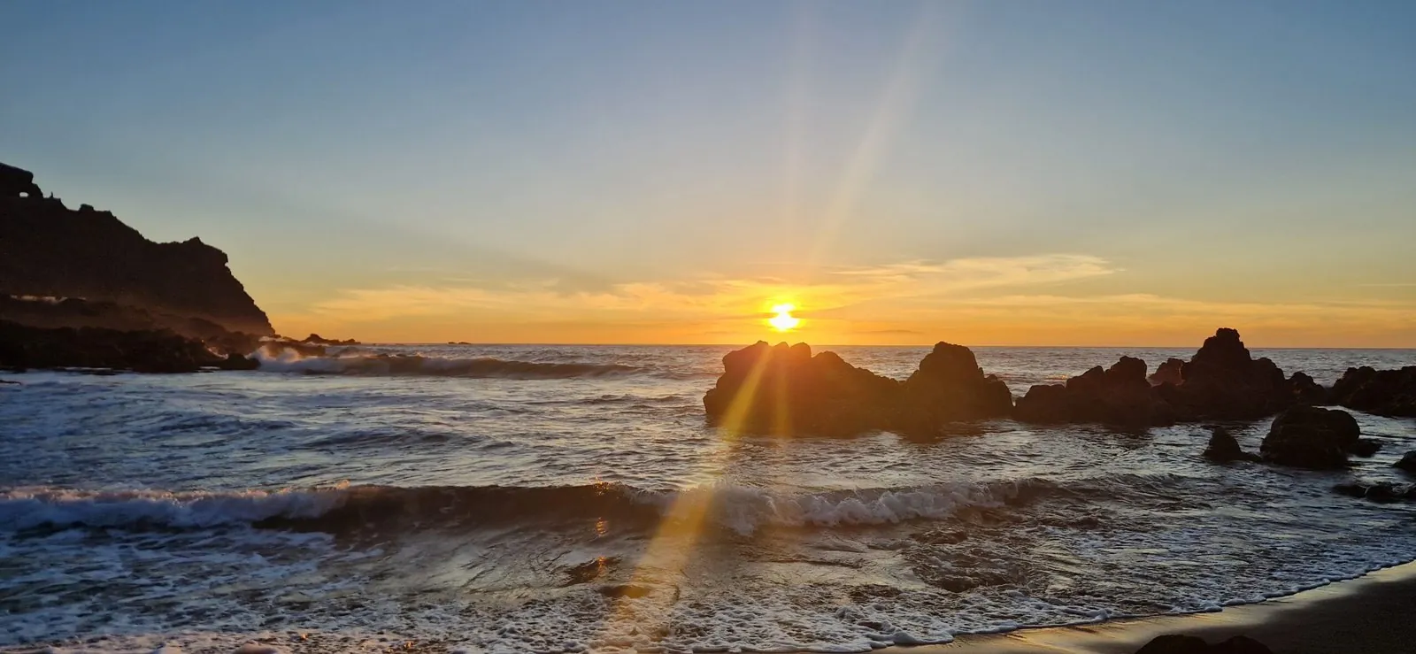 Atardecer sobre el mar con rocas en primer plano